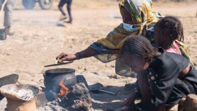 نازحة داخليا تطبخ في مكان مفتوح في مخيم البان جديد في السودان.