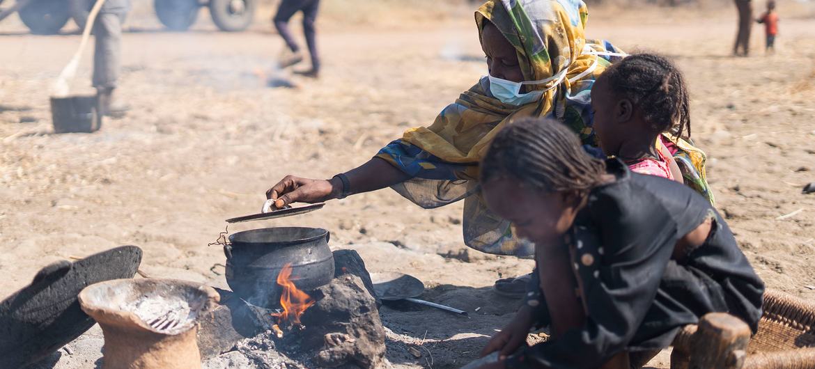 نازحة داخليا تطبخ في مكان مفتوح في مخيم البان جديد في السودان.